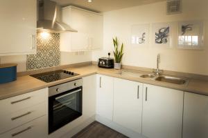 a kitchen with white cabinets and a sink at Eider Cottage in Buckie