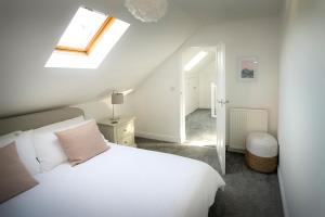 a bedroom with a white bed and a skylight at Eider Cottage in Buckie