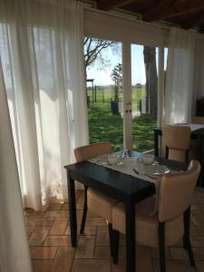 una mesa negra con sillas blancas y una ventana en B&B Casa del Bosco, en San Michele al Tagliamento