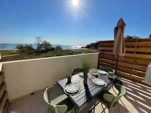 una mesa y sillas en un balcón con vistas al océano en Résidence Marina Di Bravone, en Linguizzetta