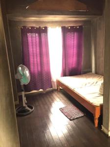 Habitación con cama con cortinas moradas y ventilador. en RedDoorz Hostel @ Madrias Pension House Isabela, en Tumauini