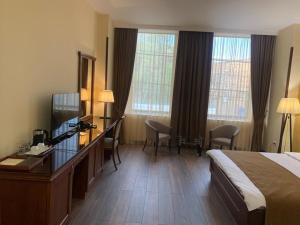 a hotel room with a bed and a desk and windows at Ararat Hotel in Yerevan