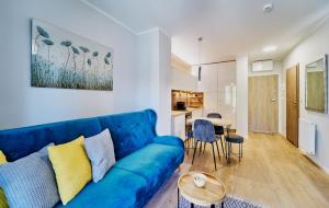 a living room with a blue couch and a table at LAGUNA Apartament Polanica Residence 38 z garażem SPA in Polanica-Zdrój