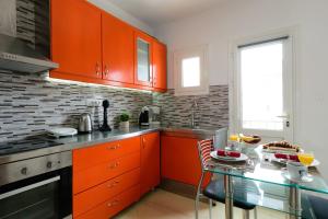 a kitchen with orange cabinets and a glass table at Luxury Lake View in Agios Nikolaos