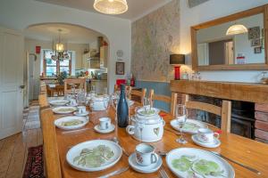 a long wooden table with plates and glasses on it at The Old Post Office in Grange Over Sands