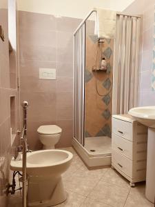 uma casa de banho com um WC, um chuveiro e um lavatório. em Nausicaa Beach and Town em Agropoli
