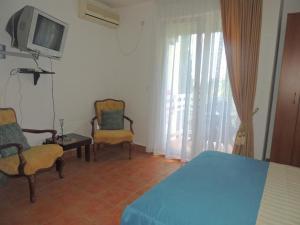 a bedroom with a bed and two chairs and a tv at Villa Seka in Budva