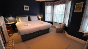 1 dormitorio con 1 cama grande con sábanas blancas y ventanas en The Moorings, en Saint Helens