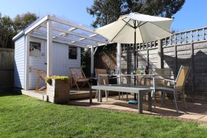 un patio con una mesa y una sombrilla en The Moorings, en Saint Helens