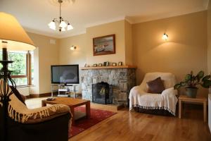 a living room with a fireplace and a tv at White Thorn House in Clifden