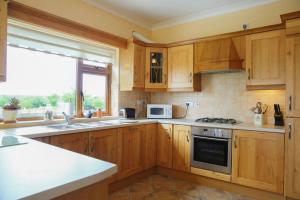 a kitchen with wooden cabinets and a stove top oven at White Thorn House in Clifden