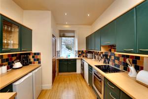 a large kitchen with green cabinets and wooden floors at Argyll Mansions in Oban