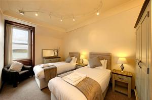een slaapkamer met 2 bedden, een stoel en een raam bij Argyll Mansions in Oban