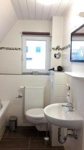 a bathroom with a sink and a toilet and a window at Küstenhuus-Katy in Glowe
