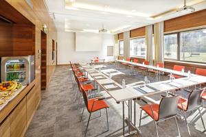 una sala de conferencias con mesas y sillas largas en Asia Hotel & Spa Leoben, en Leoben