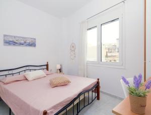 a bedroom with a bed with pink sheets and a window at fam central apt in Heraklio Town