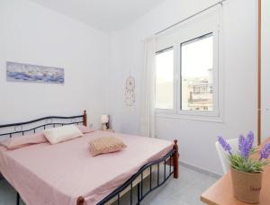 - une chambre avec un lit avec des draps roses et une fenêtre dans l'établissement fam central apt, à Héraklion