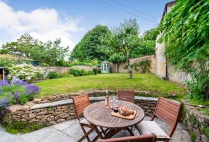 a patio with a table and chairs in a garden at Vicarage Cottage in Powerstock