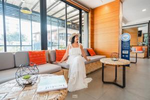 Una mujer con un vestido blanco sentada en un sofá en Cmor by Recall Hotels SHA Extra Plus en Chiang Mai