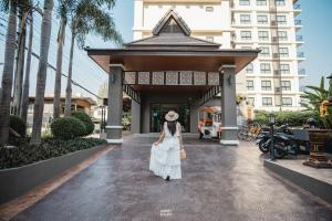 a woman in a white dress standing in front of a building at Cmor by Recall Hotels SHA Extra Plus in Chiang Mai