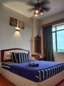 a bedroom with a bed with a ceiling fan at GloRy BeAch ResOrt private apartment in Port Dickson