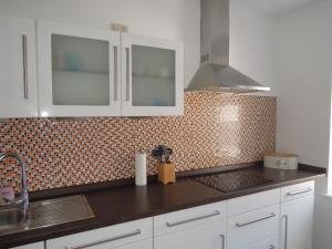 a kitchen with white cabinets and a tiled wall at Ferienwohnung Nordluft in Erfurt