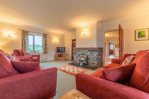 a living room with two red couches and a fireplace at September Cottage in Wadebridge