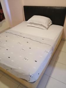 uma cama com lençóis brancos e uma cabeceira preta em Apartment at Glory Beach Resort em Porto Dickson