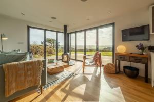 a living room with a couch and a desk and windows at The Deck House in St. Agnes 