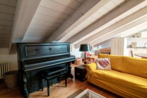 a living room with a piano and a yellow couch at Castello di Brusata by Quokka 360 - romantic flat with pool in Mendrisio