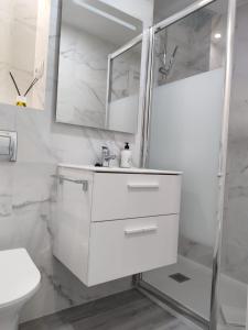 a white bathroom with a sink and a shower at Beach front Esther 5 villajoyosa in Villajoyosa