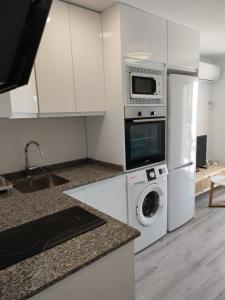 a kitchen with a washing machine and a microwave at Beach front Esther 5 villajoyosa in Villajoyosa