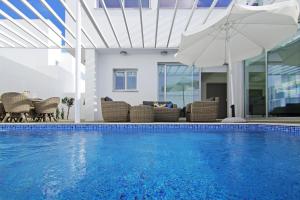 - une piscine avec des chaises, un parasol et une table dans l'établissement Villa Violanta, à Ayia Napa