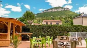 a patio with tables and chairs and a hill at Camping Larribal in Millau