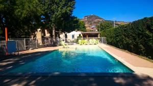 a swimming pool with chairs in a yard at Camping Larribal in Millau