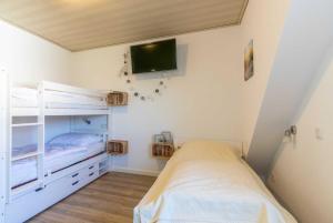 a bedroom with a bunk bed and a tv on the wall at Ferienhaus Alana in Hooksiel