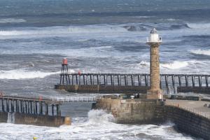 a lighthouse in the ocean next to a pier at La Rosa Hotel in Whitby
