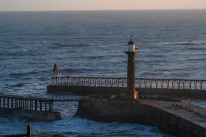 a lighthouse on a pier next to the ocean at La Rosa Hotel in Whitby