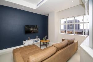 ケープタウンにある2010 Pullman Lovely 2 Bedroom apartment in the CBDの青い壁のリビングルーム(大きなソファ付)