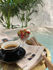 una taza de café y un tazón de fresas en una bañera de hidromasaje en Mythos Luxury Suite, en Naxos Chora