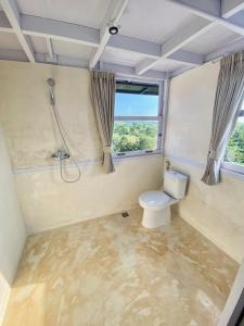 a bathroom with a toilet and a shower and a window at Uluwatu Penthouse in Uluwatu