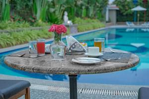 a table with a vase of flowers on it next to a pool at Sterling Gir in Sasan Gir