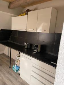 a kitchen with white cabinets and a black counter top at Bürgerstüble in Donaueschingen