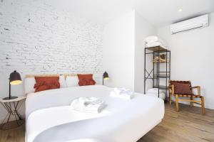 biała sypialnia z 2 łóżkami i ceglaną ścianą w obiekcie Vallecano Apartments by Olala Homes w Madrycie