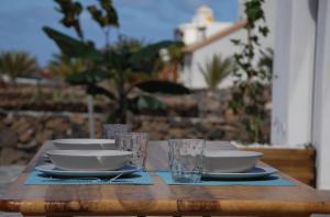 a wooden table with bowls and plates and glasses on it at MAAR House Lajares in Lajares