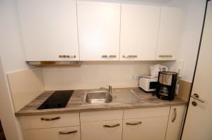 Residence Alpin - Studio-10 B by Four Seasons Apartments في كابرون: مطبخ مع دواليب بيضاء ومغسلة