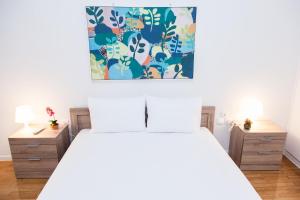 a bedroom with a white bed with a painting above it at Elegant apt in Kifisia! in Athens
