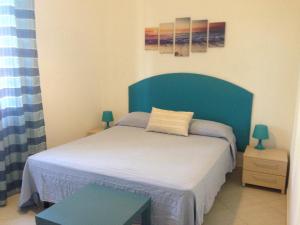 ジャルディーニ・ナクソスにあるAcquamarina Guest Homeのベッドルーム1室(ブルーヘッドボード付きのベッド1台付)