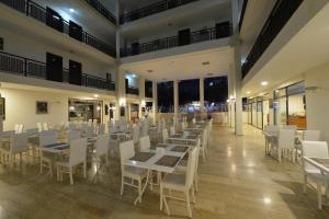 uma sala de jantar com mesas e cadeiras brancas em Kaftans City Hotel by RRH&R em Kemer