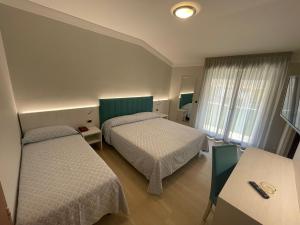 a hotel room with two beds and a table at Hotel Corallo in Fano